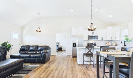 Open Floor Plan featuring Vaulted Ceilings, Stone Fireplace, Built-In Shelving, Luxury Vinyl Plank Flooring, and abundant Natural Light.