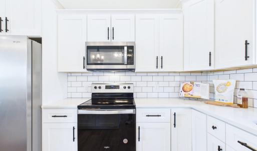 Granite Countertops, Large Kitchen Island, Stainless Steel Appliances, White Cabinetry, and Open Kitchen Design.