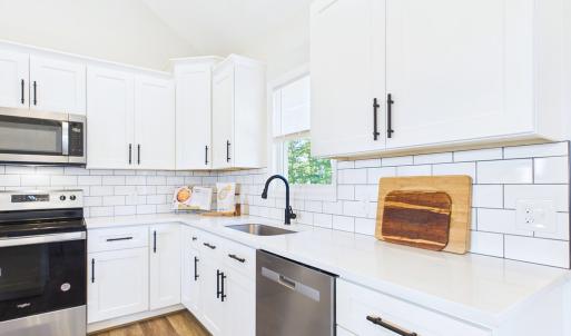 Granite Countertops, Large Kitchen Island, Stainless Steel Appliances, White Cabinetry, and Open Kitchen Design.