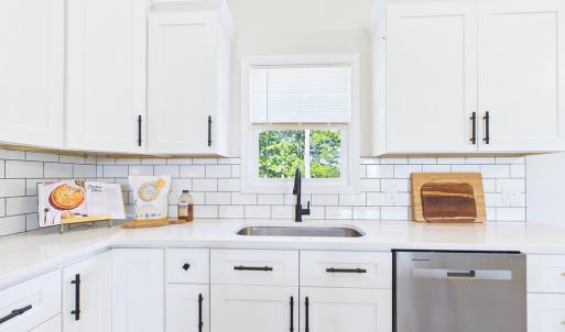 Granite Countertops, Large Kitchen Island, Stainless Steel Appliances, White Cabinetry, and Open Kitchen Design.