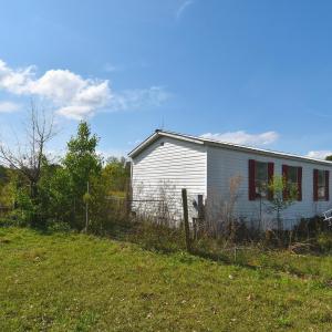 View of side of home featuring fence and a yard