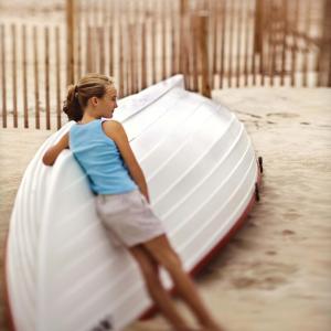 little girl leaning on boat at beach