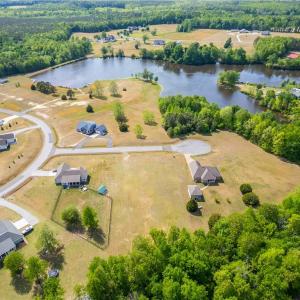 Aerial view of the 1.3 acre lot and surrounding countryside. The lot is raised, with water views towards the pond.