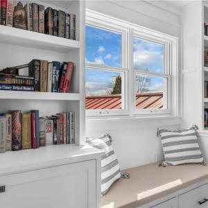 Second floor hallway w/ built in bookcases/display shelves w/ cabinet storage and day bench