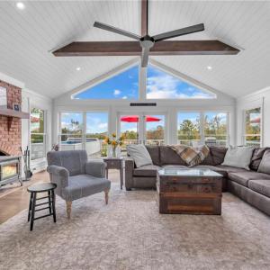 Great room w/ cathedral ceilings & exposed wooden beams, brick fireplace w/ Hearthstone wood burning cast iron stove, shiplap ceiling, and large gable window for natural light