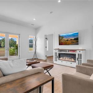 Living room w/ built in electric fireplace cabinet, LVP flooring throughout, and cathedral ceilings