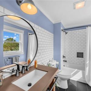 Second floor full bathroom with concrete countertop, backsplash accent wall, Pfister sink, black accent tile floor, and tub/shower combo w/ tile surround