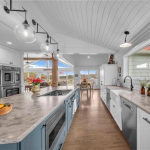 Honed quartz countertop, tile backsplash, farmhouse porcelain sink, & glass globe pendant light fixtures