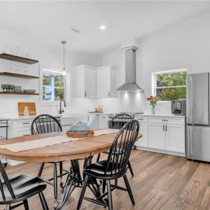 Guest house kitchen w/ Samsung appliances, 3 decorative floating shelves, and open floor plan to living room