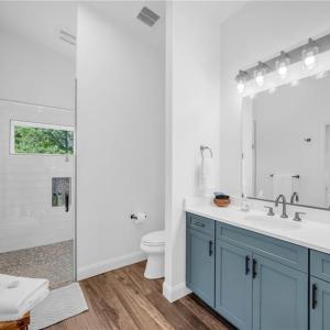 Full bathroom w/ frameless glass shower & tile surround, large vanity, and quartz countertop