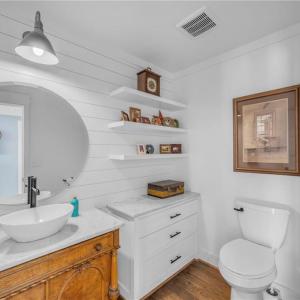 Main floor powder room w/ vessel sink and quartz countertop, 3 floating decorative shelves, and built in storage cabinet w/ quartz countertop