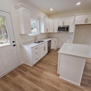 Kitchen with white cabinets, a center island, stai