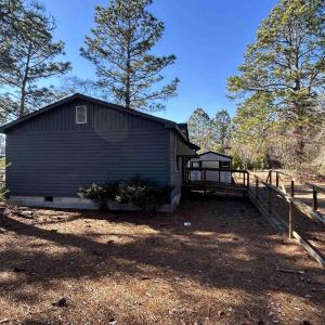 View of side of home with crawl space, fence, and