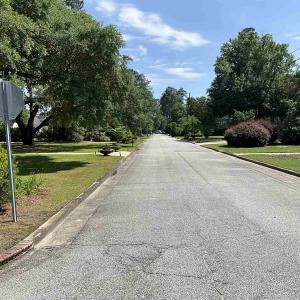 View of asphalt road with curbs, traffic signs, an