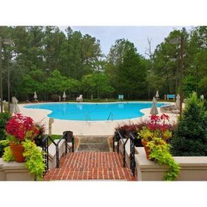 Community pool with a patio and view of wooded are