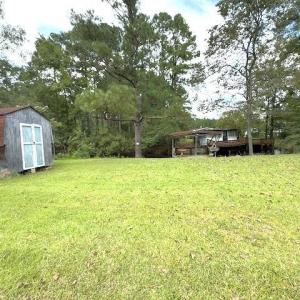 View of grassy yard featuring a shed and a wooden