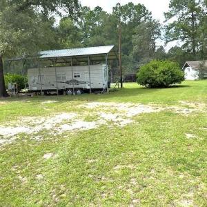 View of grassy yard featuring view of scattered tr