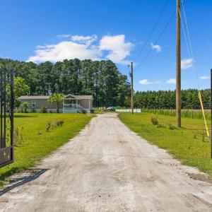 View of dirt / gravel driveway featuring a gate an