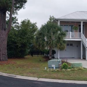 Raised beach house with stairs, driveway, and a ga