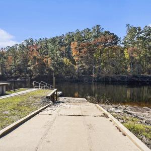 Dock with a boat ramp, a water view, and a forest