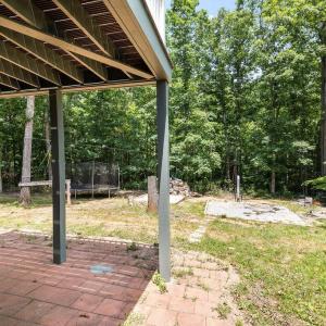 From the exterior downstairs door, you walk onto the brick patio under the upper deck ... ahead are all the fun activities! There is a zip line strong enough for adults to use! The trampoline can convey and it has been carefully leveled, the feet are buried 18" deep, new protective net, springs and bouncy floor. Straight ahead almost hidden is a real tree house! And sandbox, and pad for above ground pool with a wood heater for the pool! Don't forget a trail in the woods!