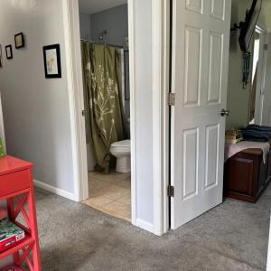 The Primary suite is the first door on the right. The hall bathroom for the other 3 bedrooms is shown here. Opposite the red table is the entrance to the 2nd bedroom.