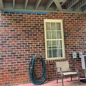 Outside this door is the upper deck. The bottom of the foundation is brick. The siding above it is vinyl. The seller created a patio here with terra cotta bricks. It is a great place to sit in the shade to still enjoy being outside on a hot summer day.