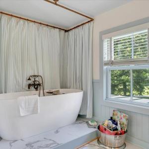 The freestanding Grecian tub is elegantly framed by a custom copper shower curtain railing.