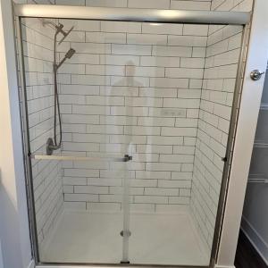 Primary bath shower floor to ceiling ceramic tile, glass door