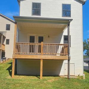 Rear of home showing covered deck with French doors from the formal DR and crawlspace door to bottom right