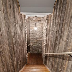 Stairs down to the basement area that has been made to replicate a wine cellar with wood and stone walls