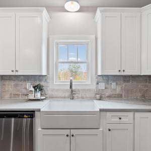 Kitchen has large island, stainless steel appliances, farmhouse sink, beautiful, upgraded lighting fixtures, quartz and stone backsplash