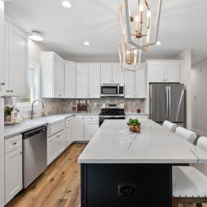 Kitchen has large island, stainless steel appliances, farmhouse sink, beautiful, upgraded lighting fixtures, quartz and stone backsplash