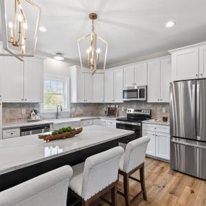 Kitchen has large island, stainless steel appliances, farmhouse sink, beautiful, upgraded lighting fixtures, quartz and stone backsplash