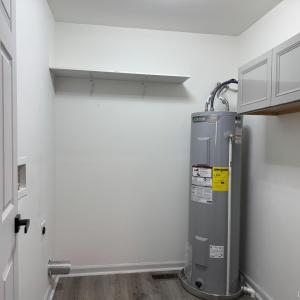 water heater, cupboard and panel box in the room with the washer and dryer. Right off the kitchen