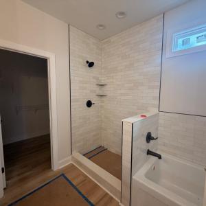 primary bathroom with double vanity sinks, tub and tile shower.