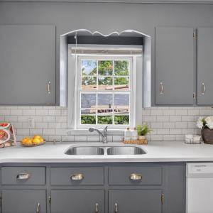 Updated kitchen with subway tile, backsplash, quartz counters, hardwood floors, and a walkout back porch. Window view over sink.