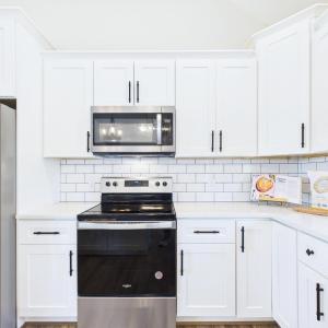 Granite Countertops, Large Kitchen Island, Stainless Steel Appliances, White Cabinetry, and Open Kitchen Design.