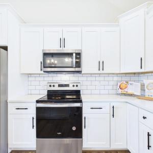 Granite Countertops, Large Kitchen Island, Stainless Steel Appliances, White Cabinetry, and Open Kitchen Design.