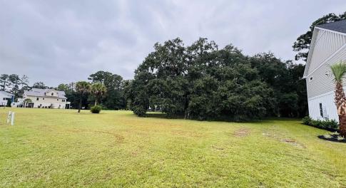 View of green lawn featuring view of wooded area